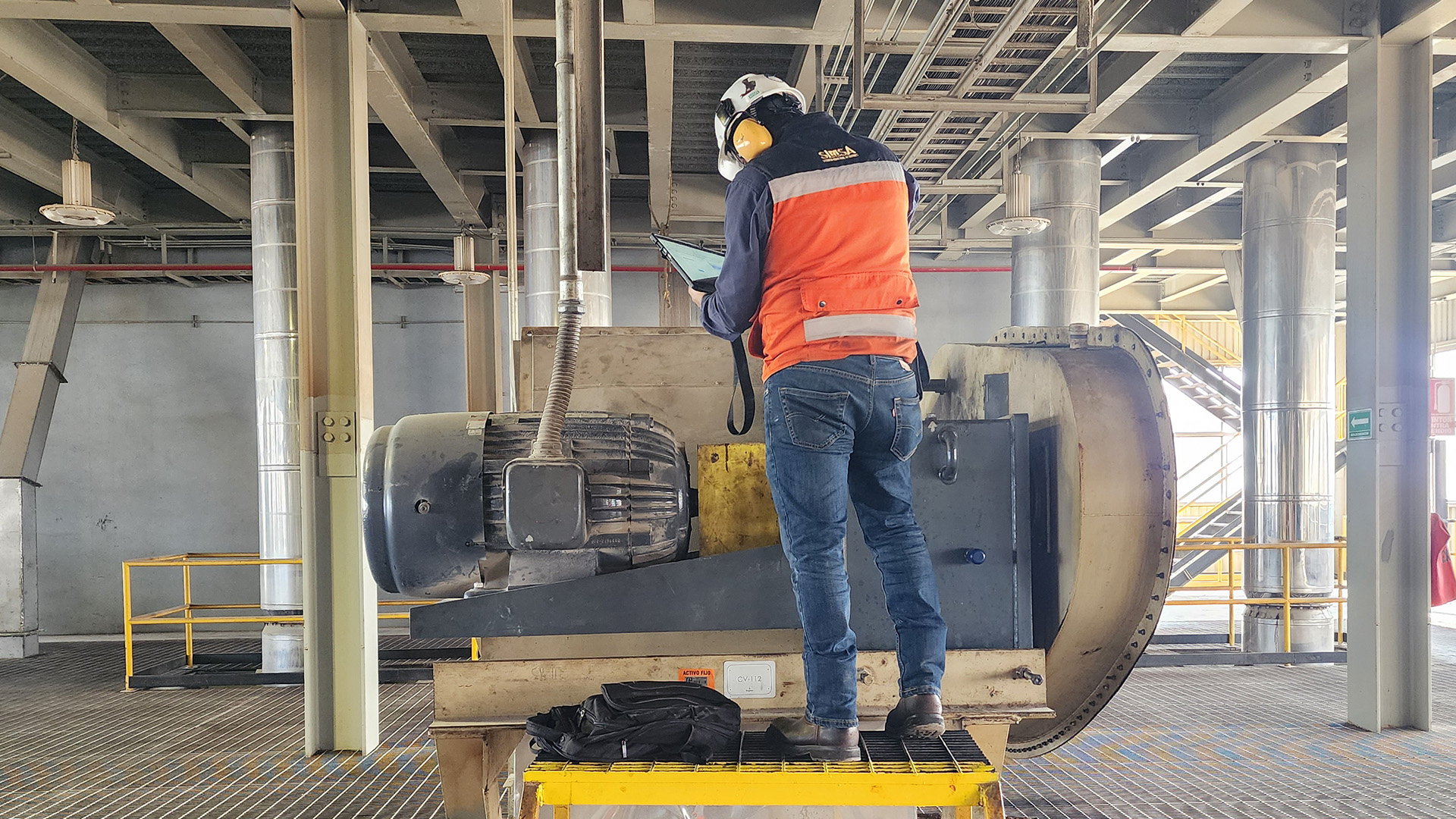 Técnico especialista realizando diagnóstico digital y monitoreo de condición a un motor eléctrico industrial.