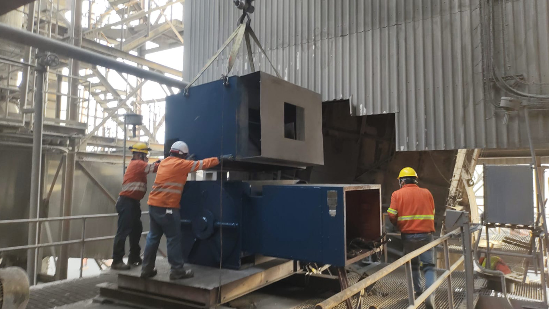 Equipo de operarios realizando maniobra crítica de izaje y posicionamiento de componentes industriales con grúa.